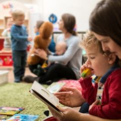 Mother and young son looking at a book in a play area