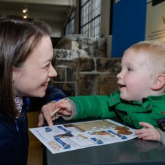 Mother and male toddler complete activity sheet at a museum