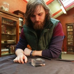 Tom Bell with the 11,000 year old engraved shale pendant discovered by archaeologists during excavations at the Early Mesolithic site at Star Carr in North Yorkshire. Image taken at the Yorkshire Museum, York. Credit: Suzy Harrison