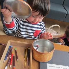 Child opens lid of a tin containing pencils to do some drawing at York Art Gallery.