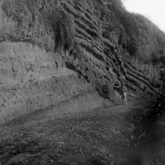 Black and white photo of gentleman stood next to a cliff face