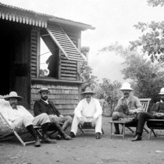 Black and white photo of five seated men wearing hats