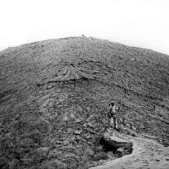 Black and white photo of barren landscape with figure on a path