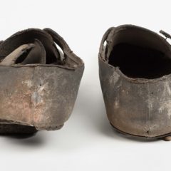 A pair of men's leather shoes. The shoes are very worn and have dabs of paint on them.
