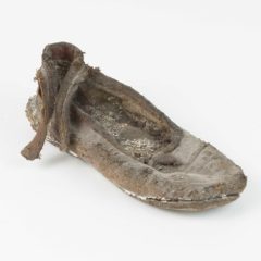 A child's leather shoe. The shoe is very worn.
