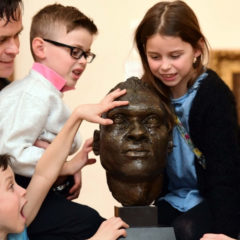 A family admiring a head sculpture.