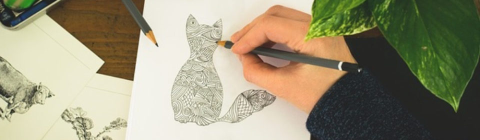 A person drawing a cat on a sketchbook.