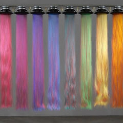 Long strands of hair descending from light shades in the ceiling. Each strand is a different colour ranging from pink to red.