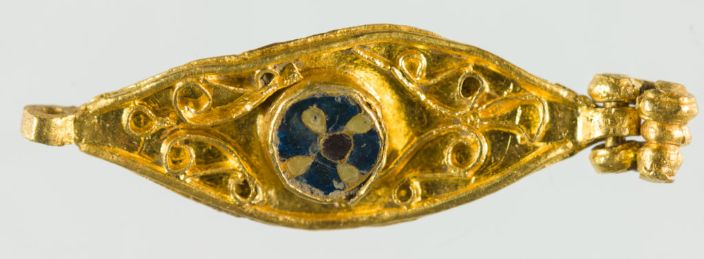 A gold brooch with a patterned circle in the middle.