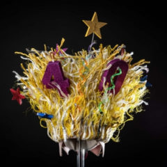 A piece of headgear made of various coloured ribbons and stars, with the numbers 4 and 0 poking out of it.