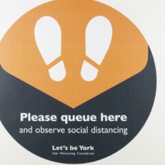 Black and Orange 'Please queue here' sign from York City Council